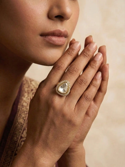 Close-up of a woman's hand wearing a ring with a large diamond, against a neutral background.