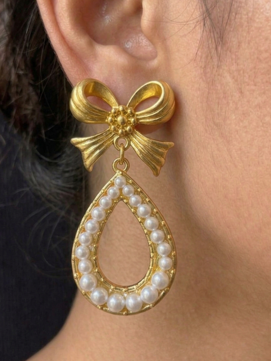 Vintage-inspired gold-tone drop earrings featuring a delicate bow and pearl border
