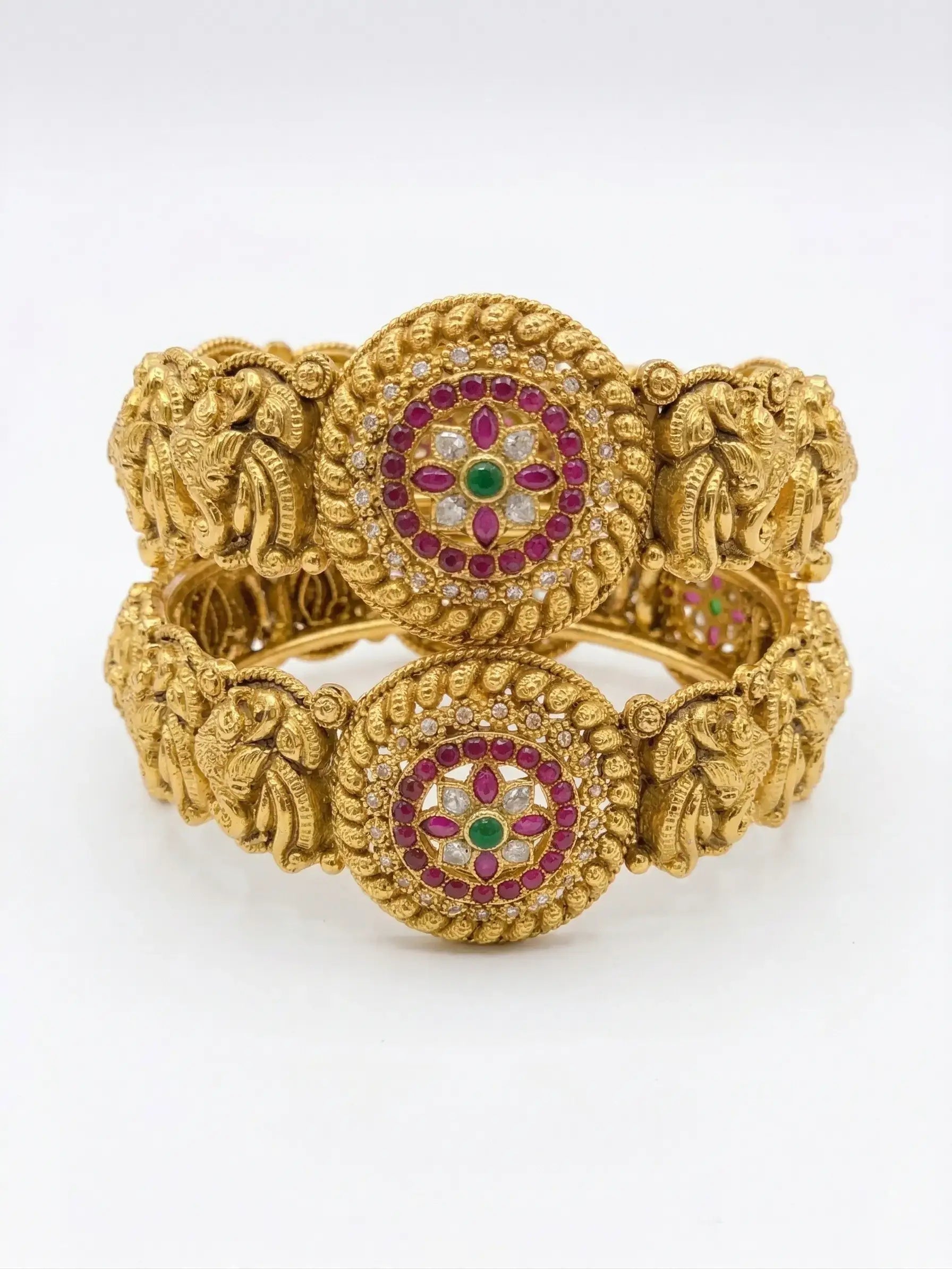 Gold bracelet with intricate designs and gemstones on a white background