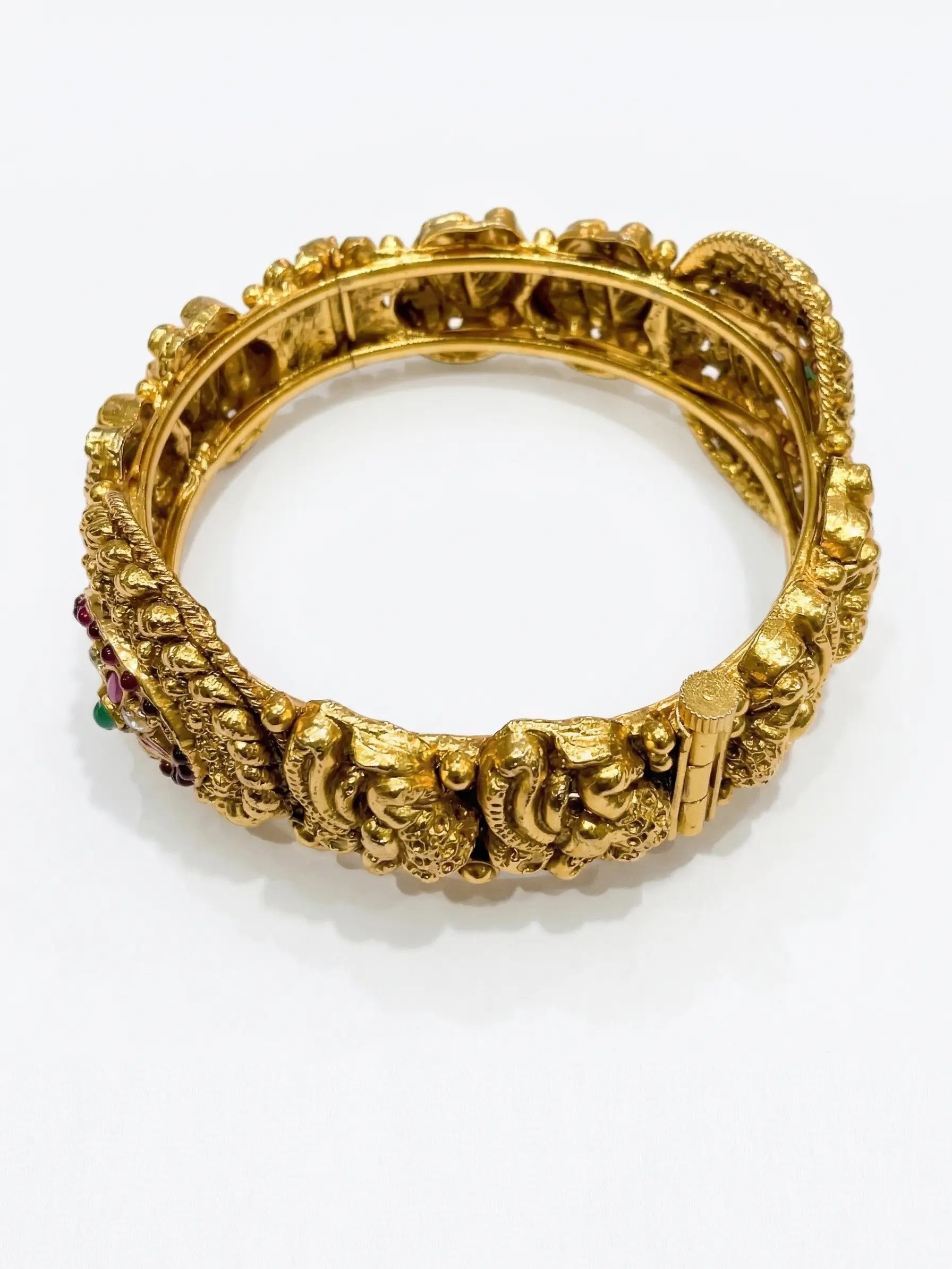 Gold bracelet with intricate design on a white background