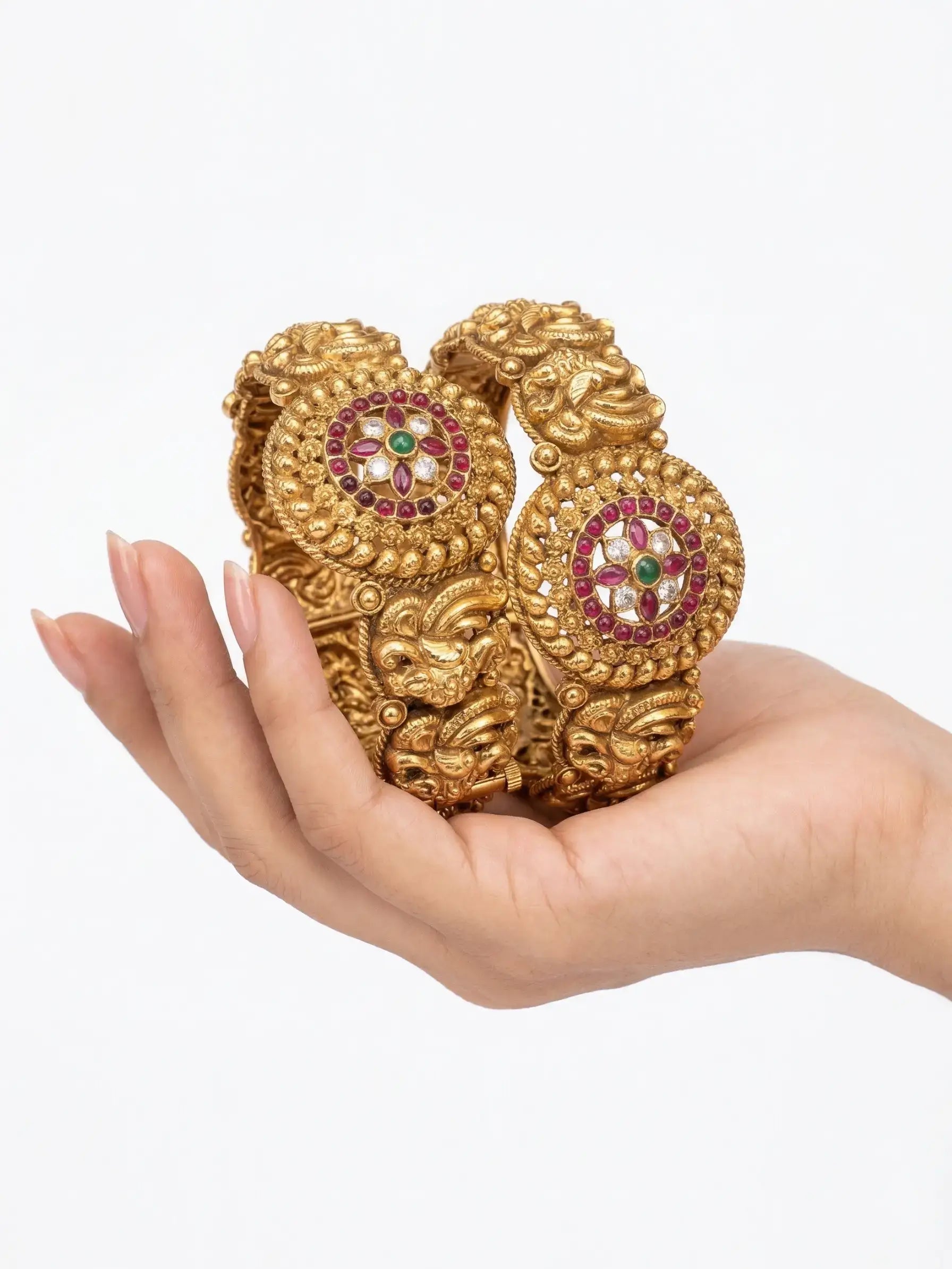 Gold bracelet with gemstones held in a hand against a white background