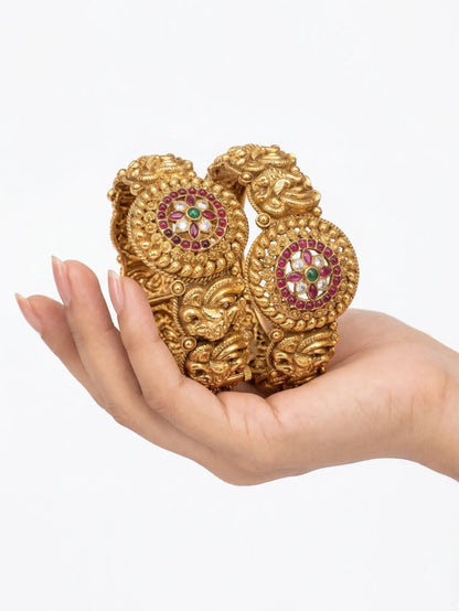 Gold bracelet with gemstones held in a hand against a white background