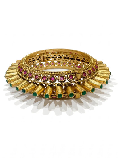 Gold bracelet with red and green gemstones on a white background