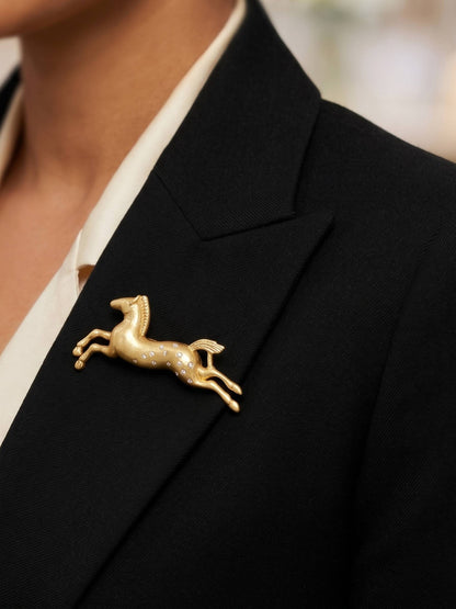 Gold horse-shaped brooch with embedded stones on a white background