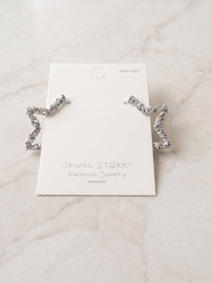 Silver star-shaped earrings on a 'Jewel Street' branded card against a light marble background.