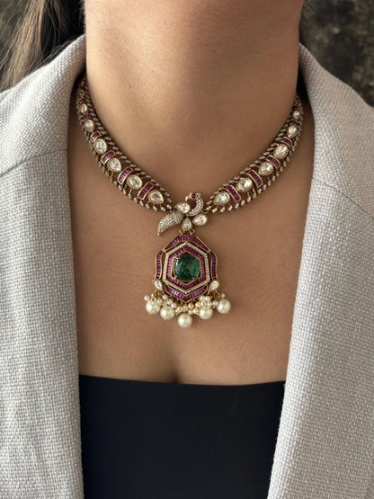 Close-up of a decorative necklace with gemstones and pearls on a person wearing a light-colored blazer.