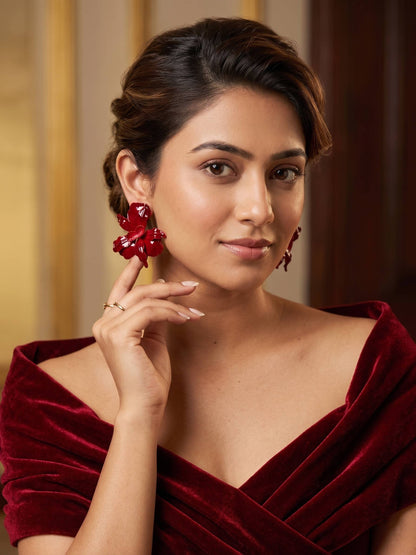 Woman wearing a red velvet outfit with red earrings against a blurred background
