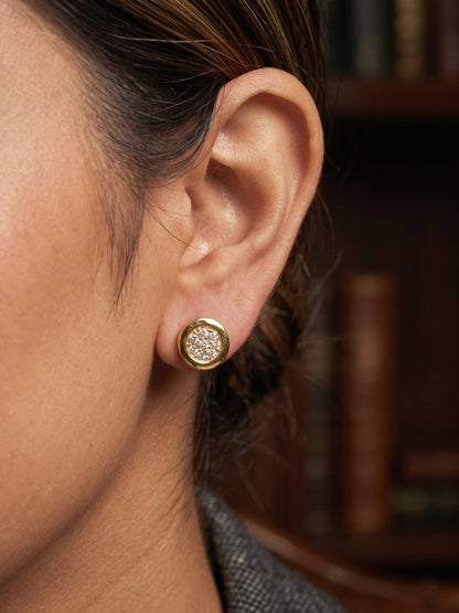 Close-up of an ear wearing a gold earring with a blurred background