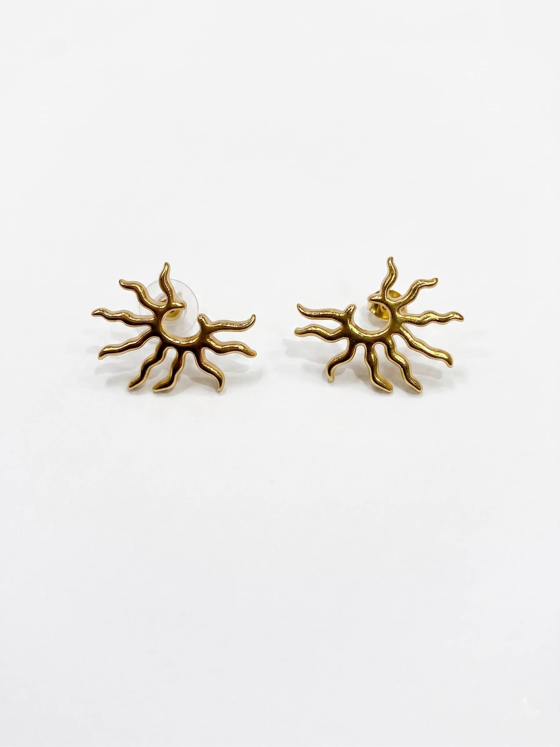 Gold sun-shaped earrings against a white background