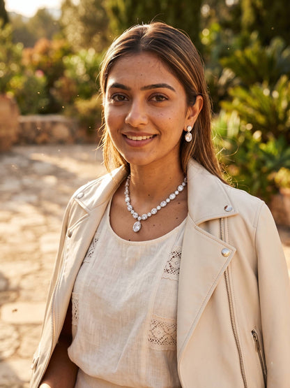 Woman wearing a beige coat and white dress with jewelry outdoors