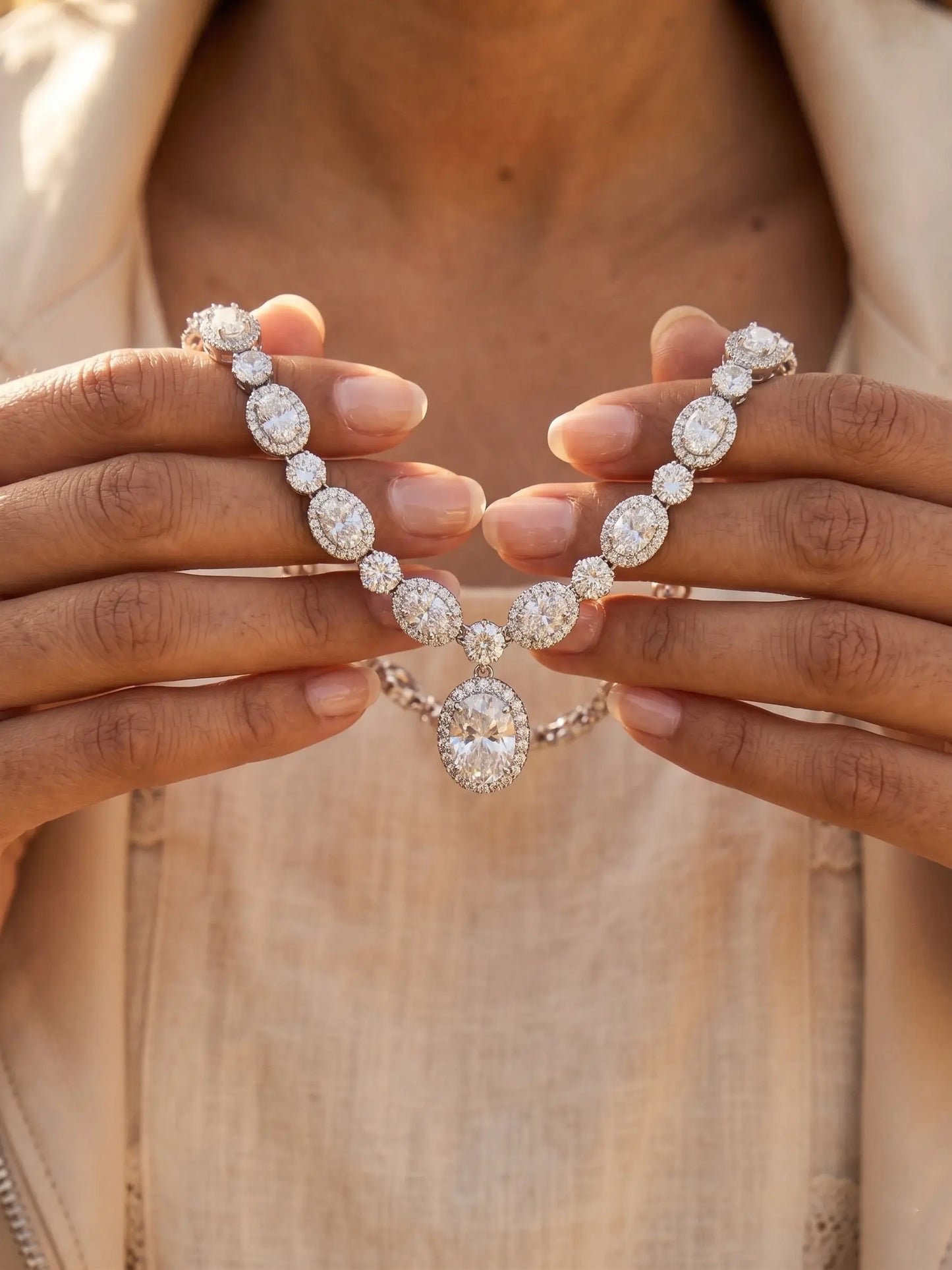 Diamond bracelet held between two hands against a neutral background