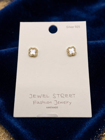 Gold earrings on a 'Jewel Street' branded card against a blue velvet background