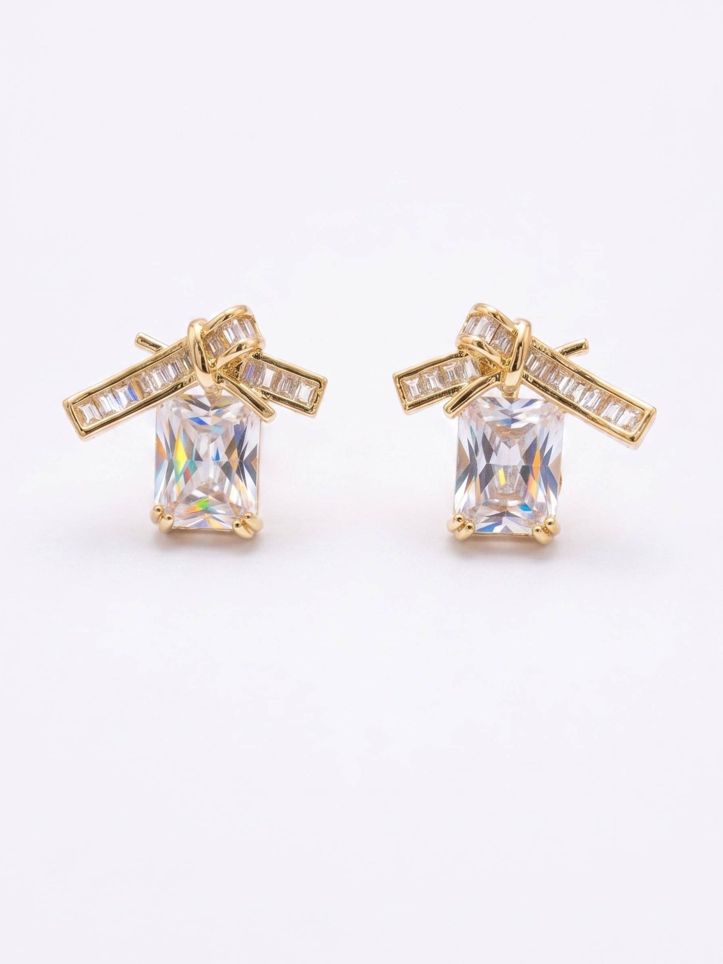 Gold earrings with clear gemstones on a white background