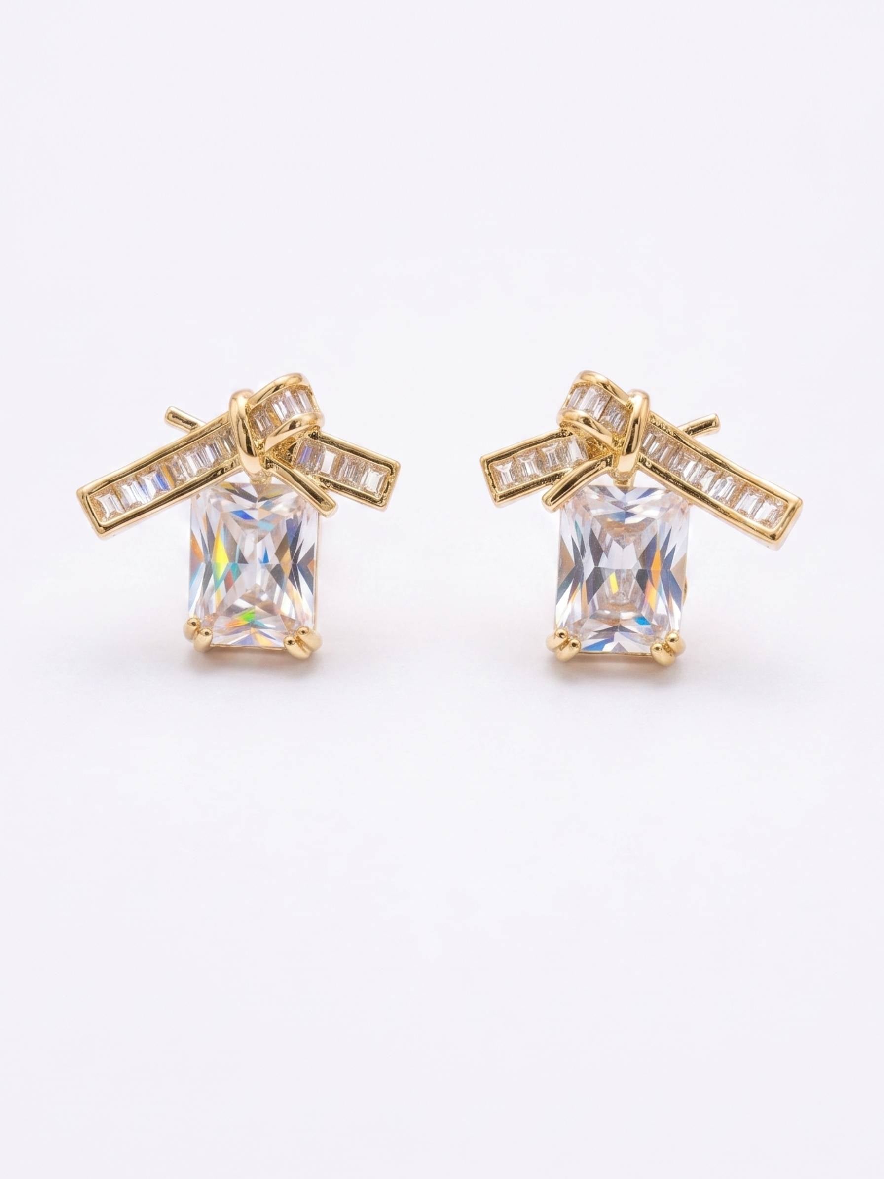 Gold earrings with clear gemstones on a white background