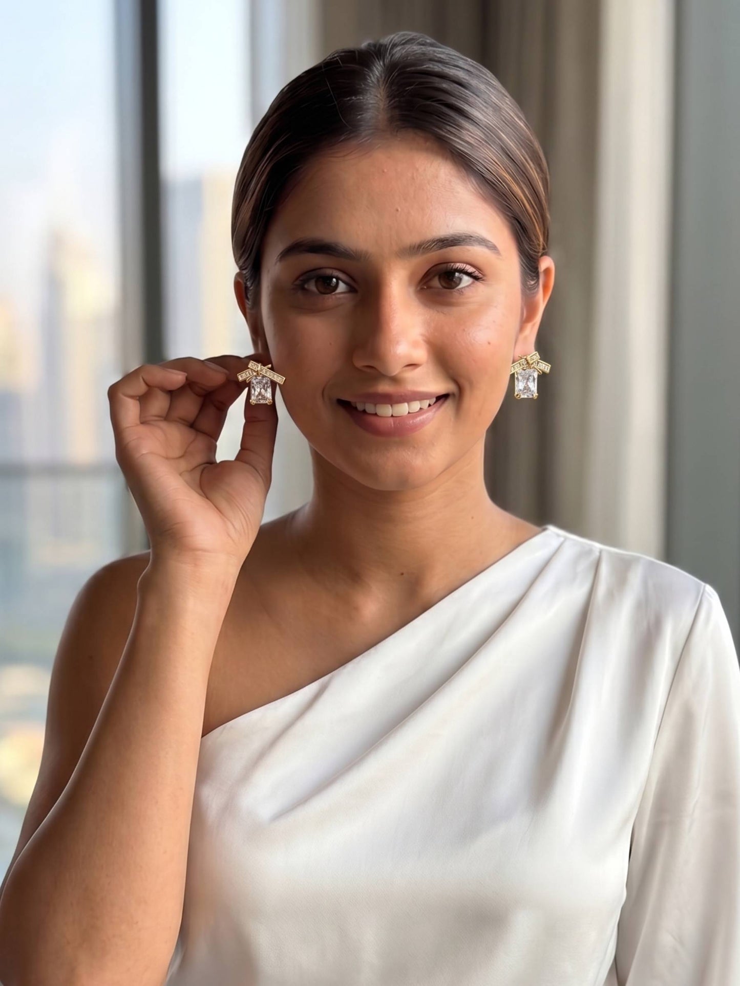 Woman wearing a white saree with diamond earrings indoors