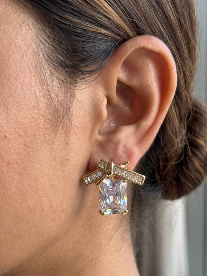 Gold earring with a large clear gemstone worn by a person.