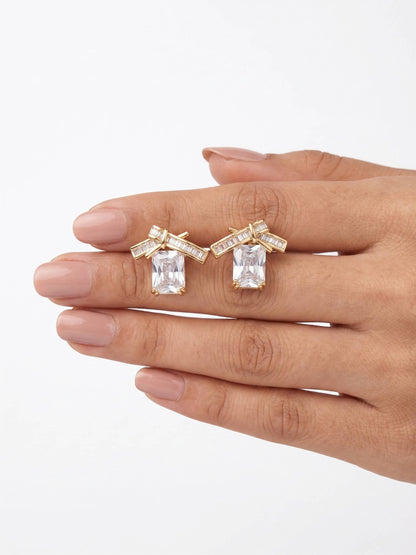 Gold and diamond earrings on a hand against a white background
