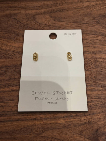 Gold earrings on a 'Jewel Street' branded card against a wooden background