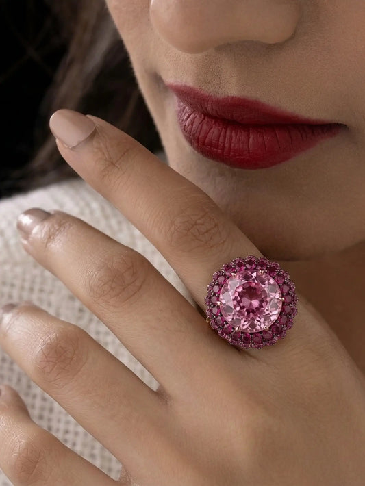 Close-up of a luxurious women ring with a unique rose-cut, blooming flower-patterned magenta pink stone, surrounded by a detailed pave halo on an adjustable band.