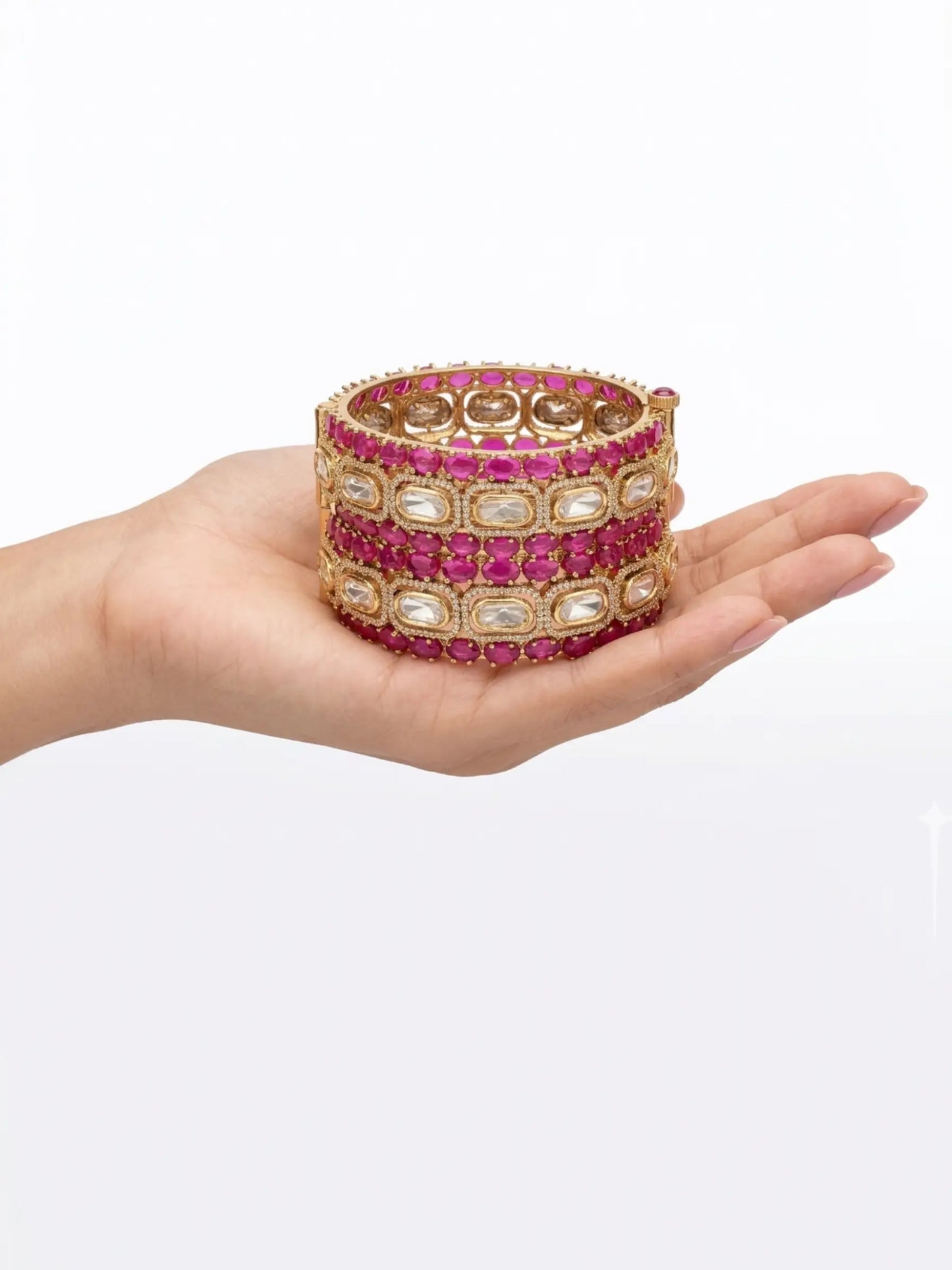 Hand holding a stack of pink ruby bangles on a white background