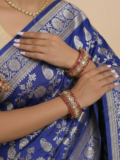 Blue saree with silver patterns worn by a person, focusing on hands with jewelry.