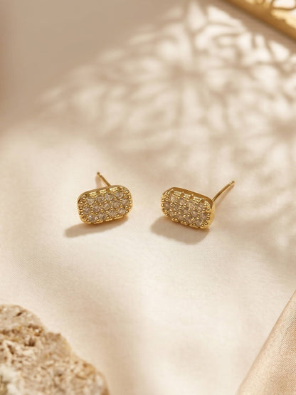 Gold earrings with a textured design on a beige surface